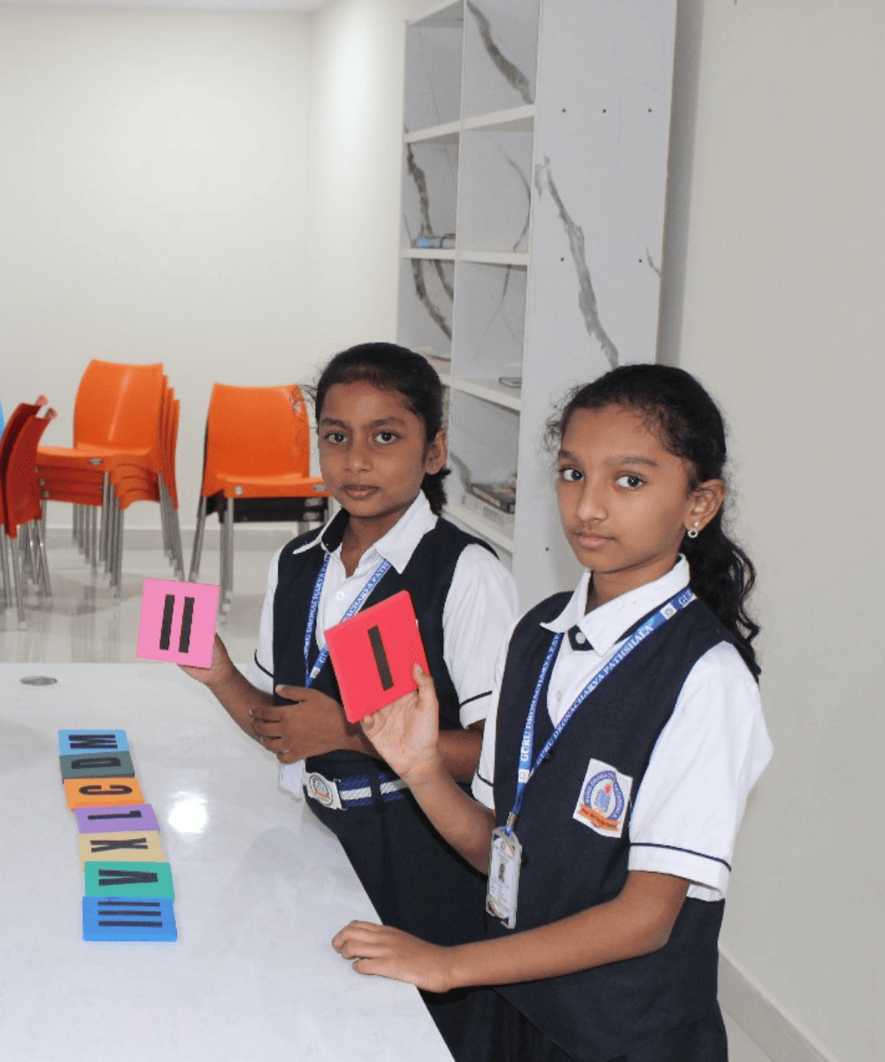 Students in a classroom at GDP holding up letter and number cards during an interactive learning session.