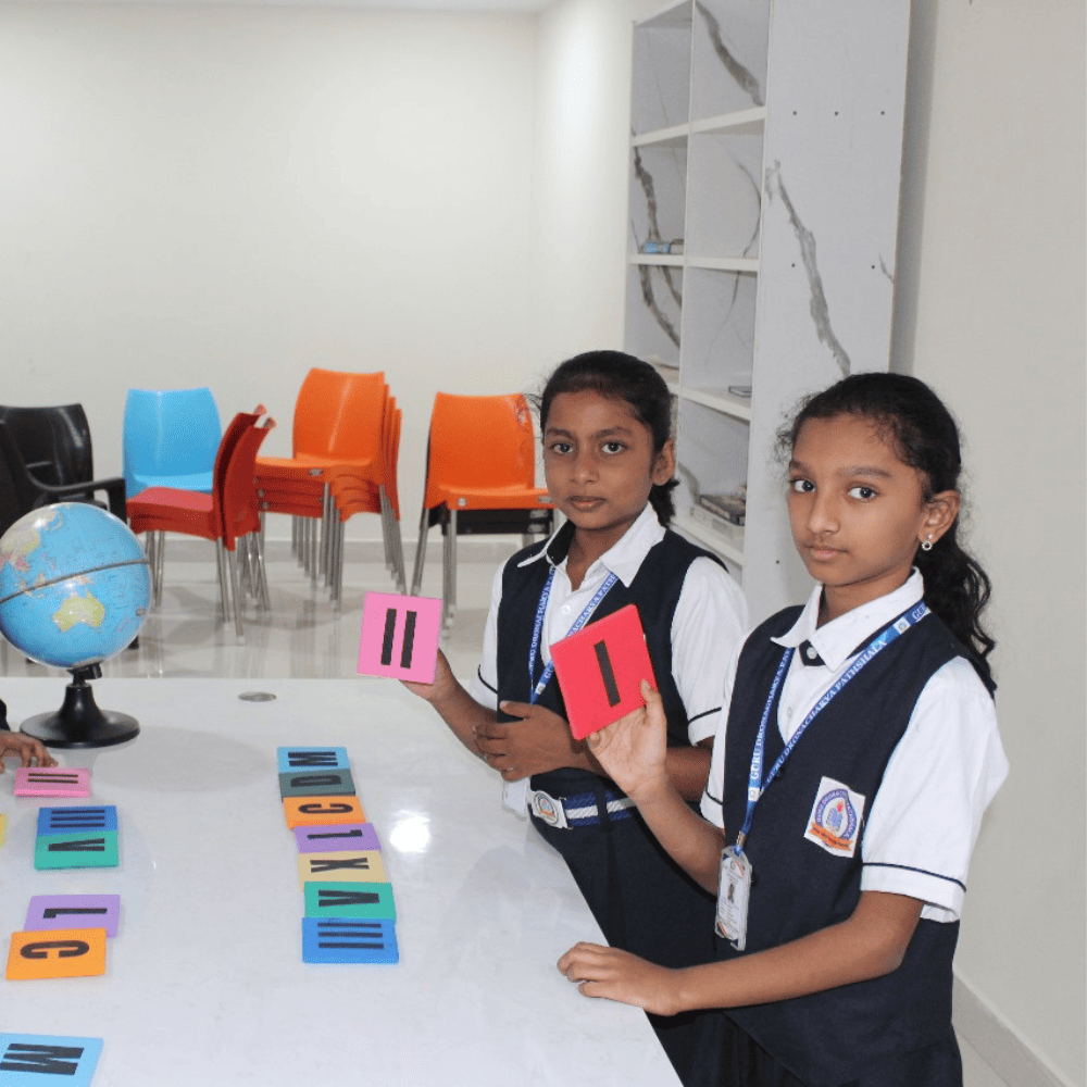 Two students in uniform holding up Roman numeral cards during an interactive mathematics learning activity.