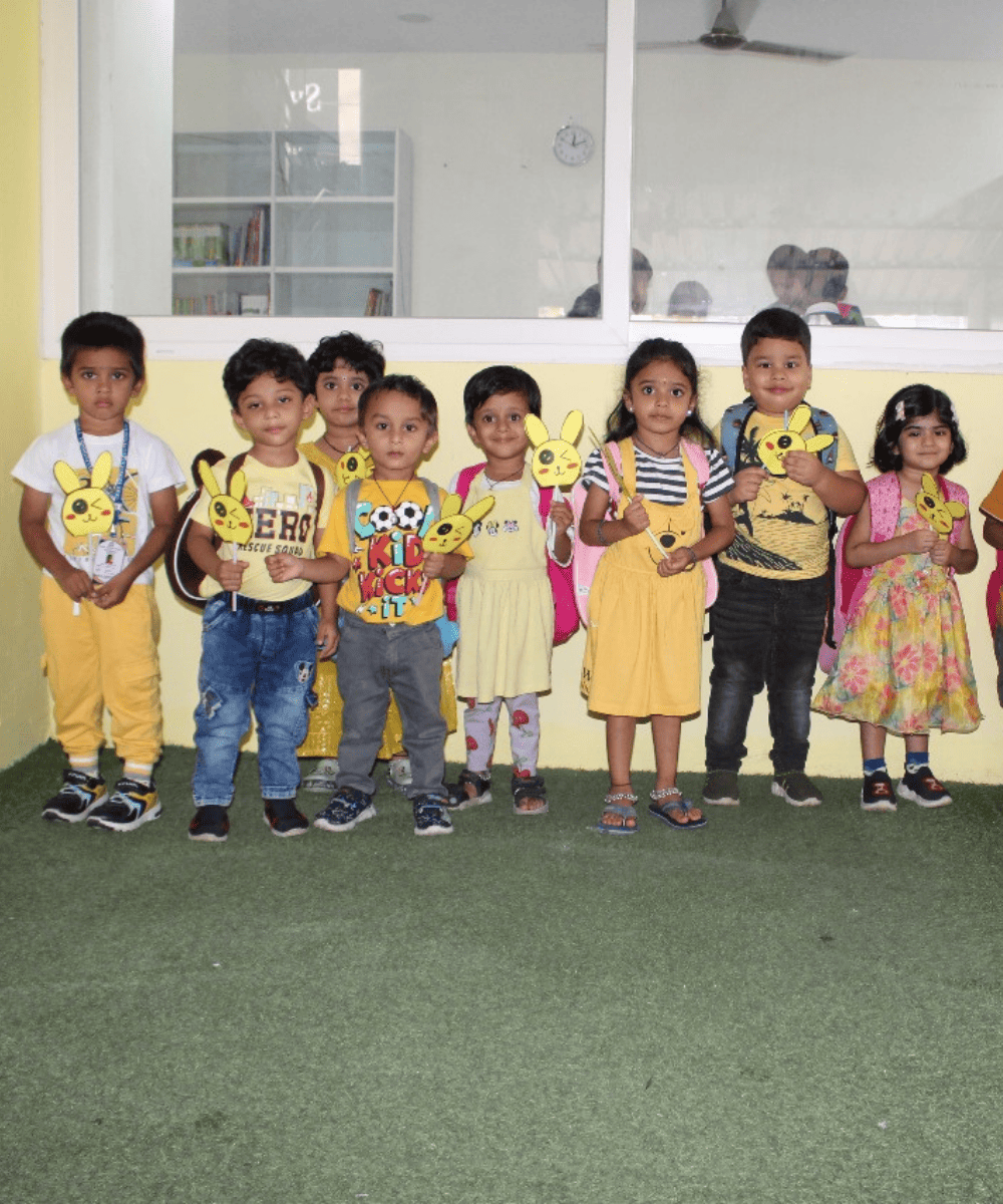 A group of proud preschool students at GDP holding up the paper crafts they made in their classroom.